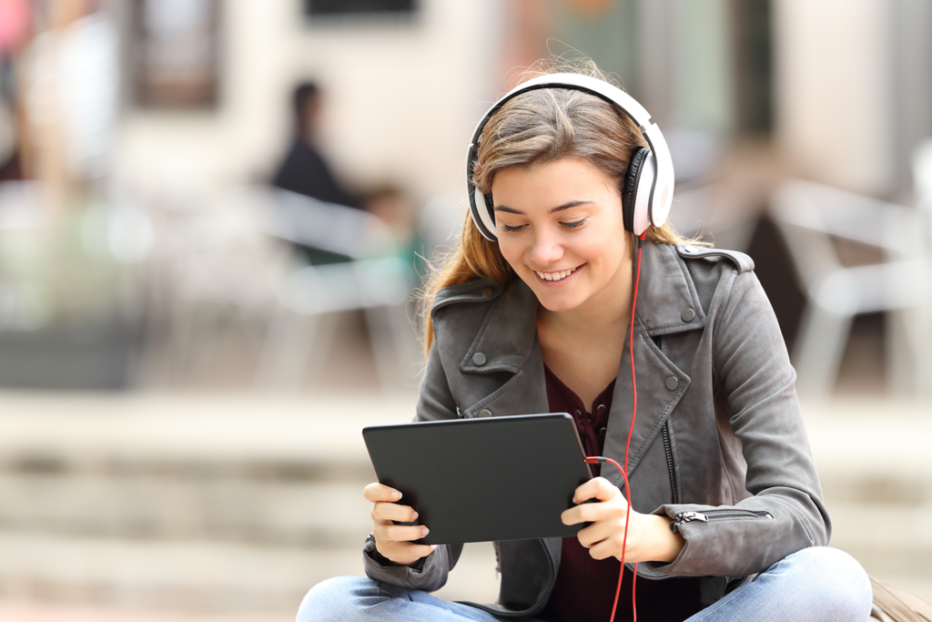 Young woman smiling at a tablet device with headphones on
